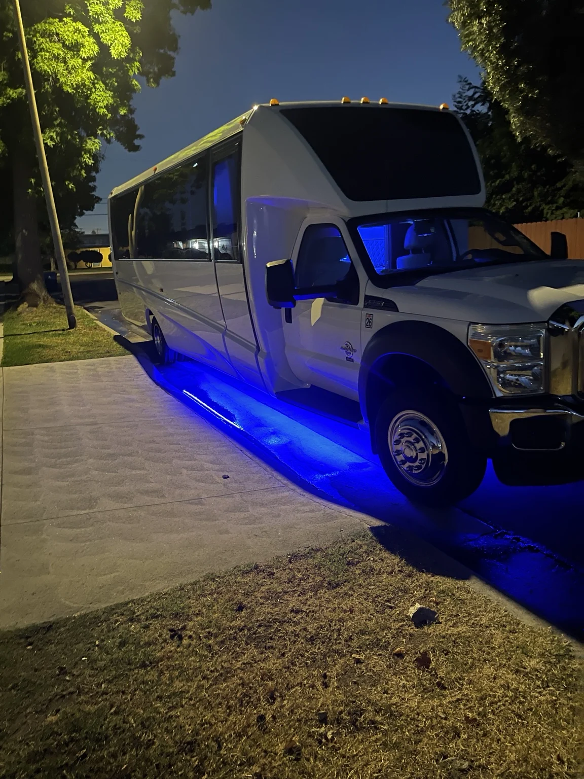 White party bus at night with blue exterior lighting