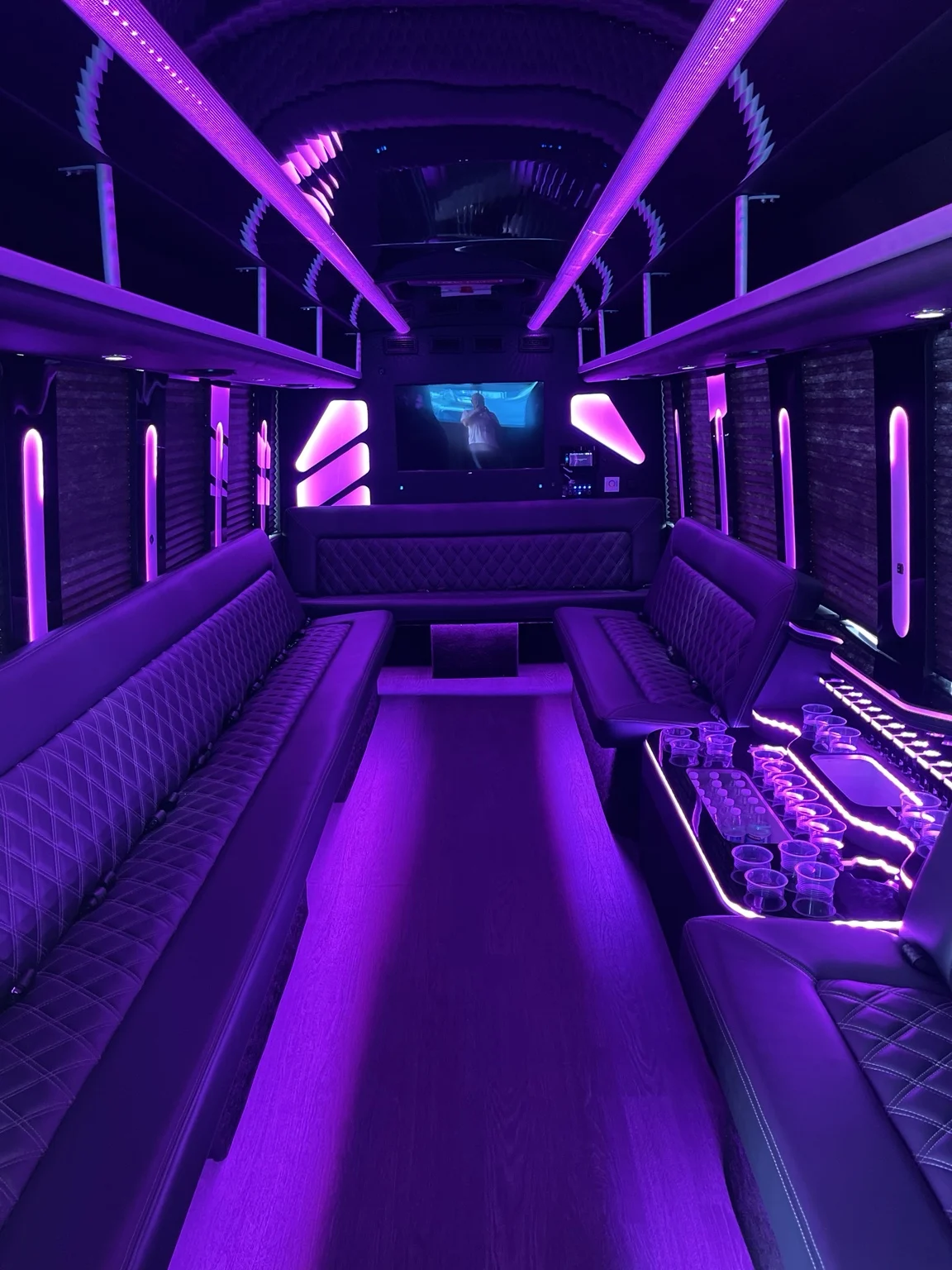 Party bus interior with purple LED lights and lounge seating
