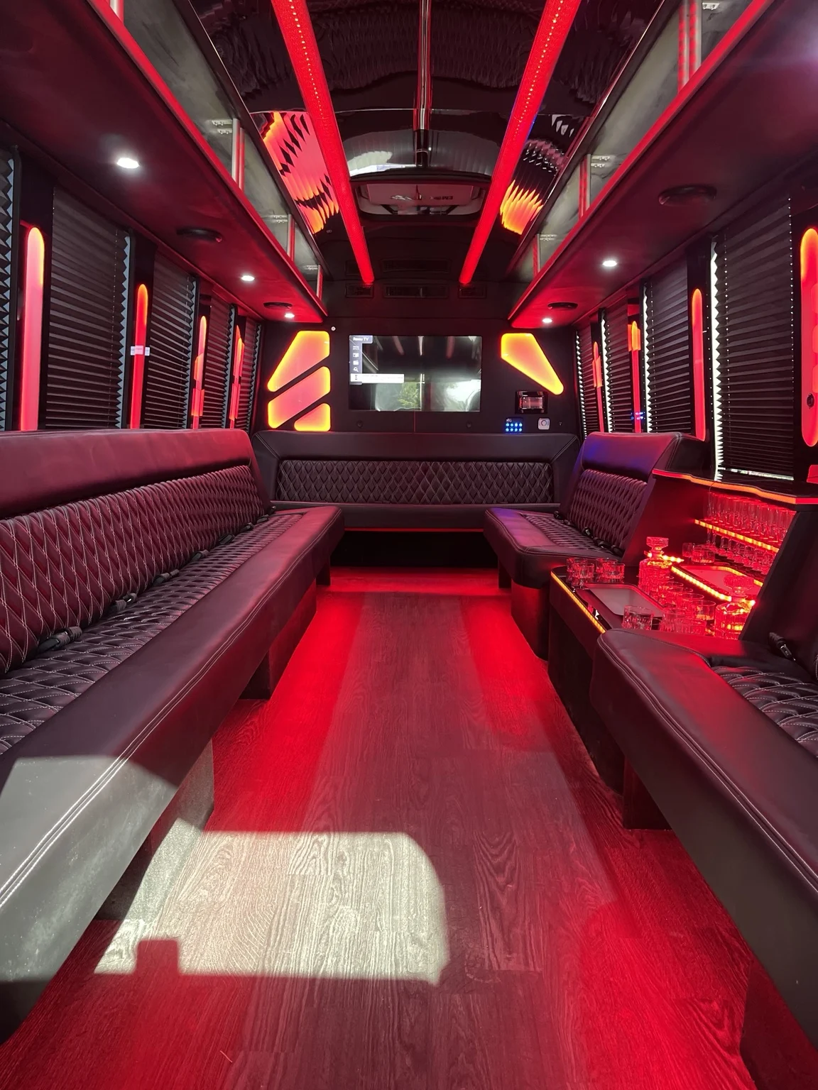 Party bus interior with red lighting and black quilted seating