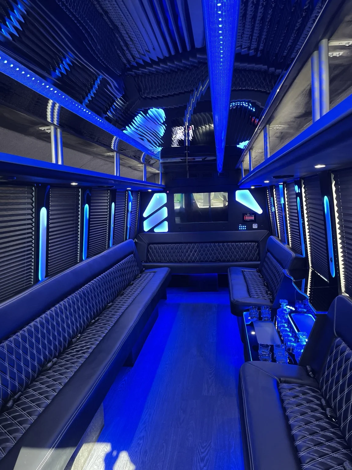 Party bus lounge with blue ceiling lights and seating along both sides