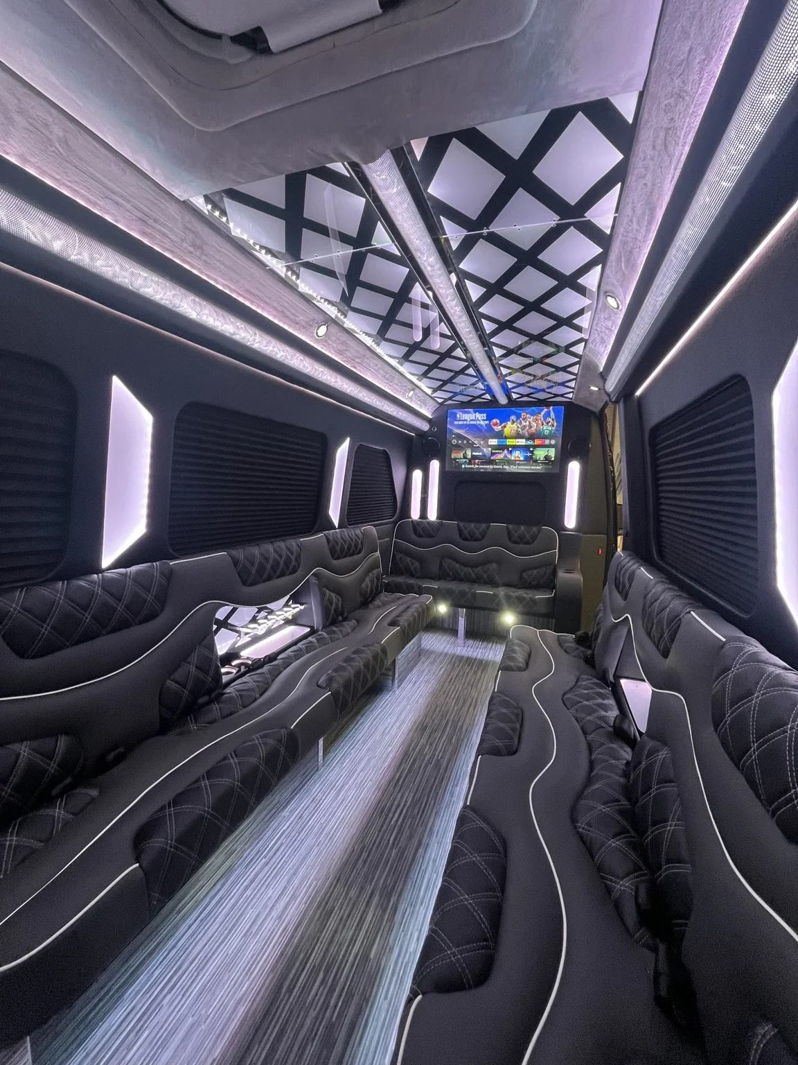 Vehicle lounge interior with wraparound seating and geometric ceiling