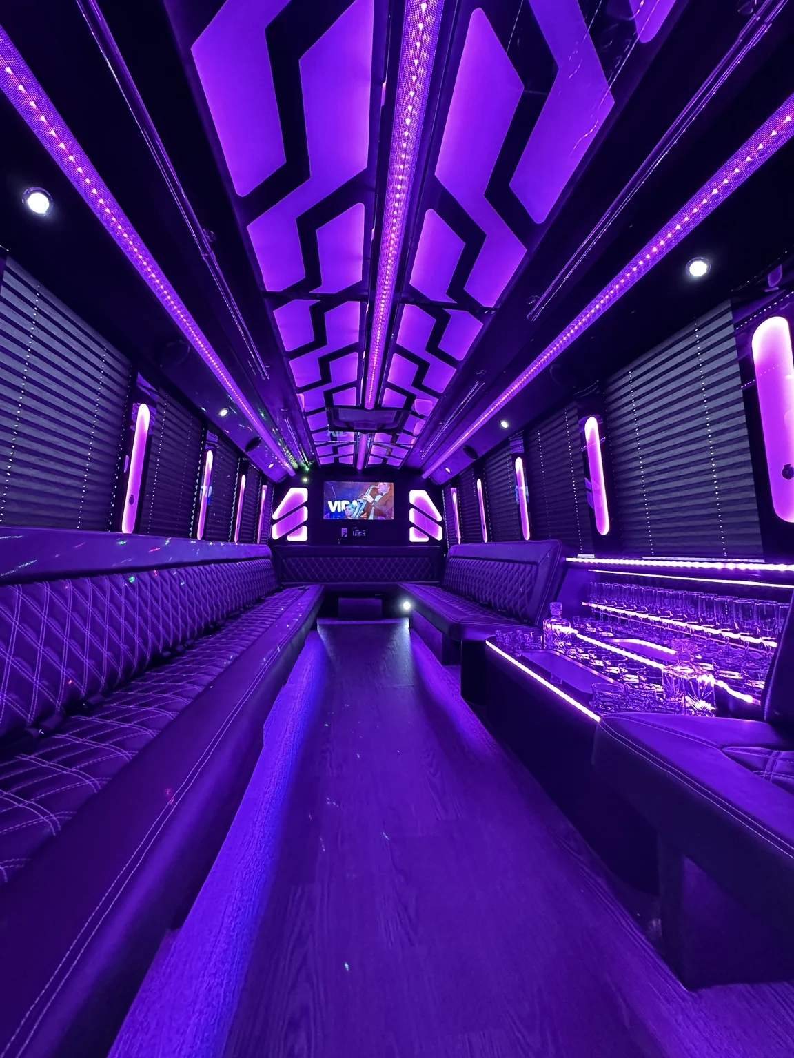 Party bus lounge with violet ceiling lights and quilted seating