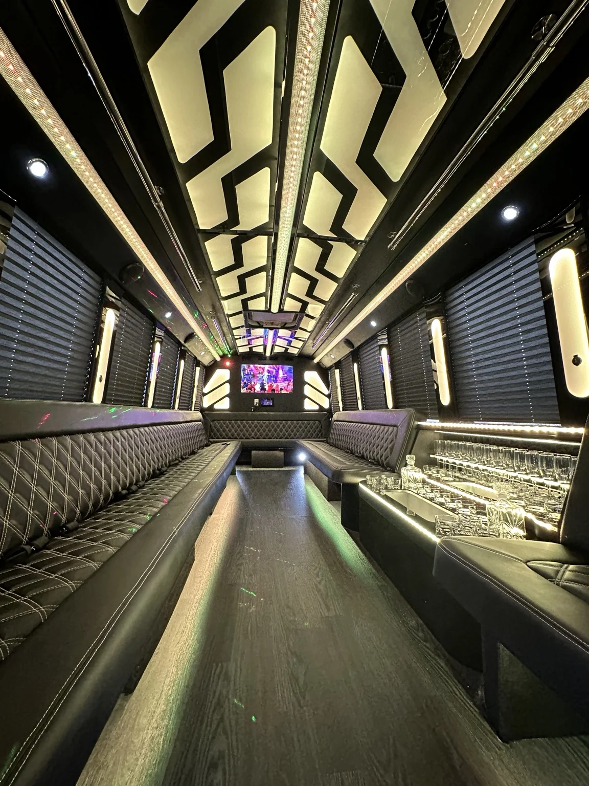 Party bus lounge with warm ceiling lighting and glassware display